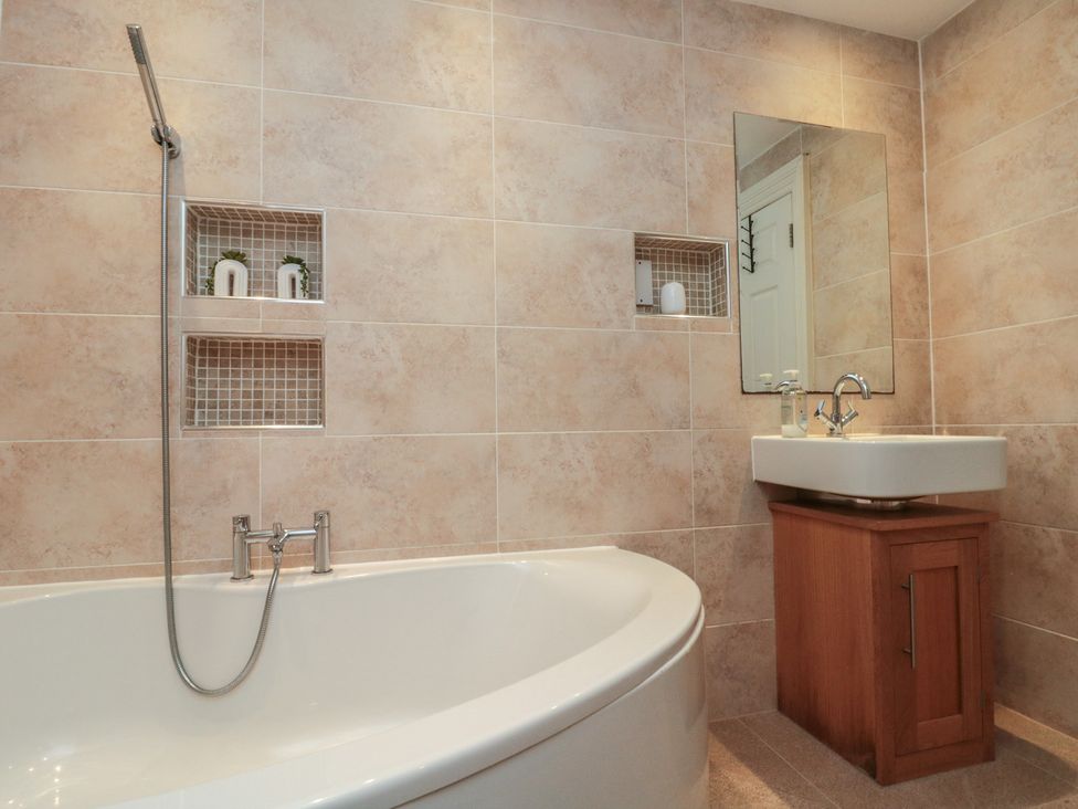 A bathroom with a bathtub and sink with a mirror at Apartment 6 in Whitby