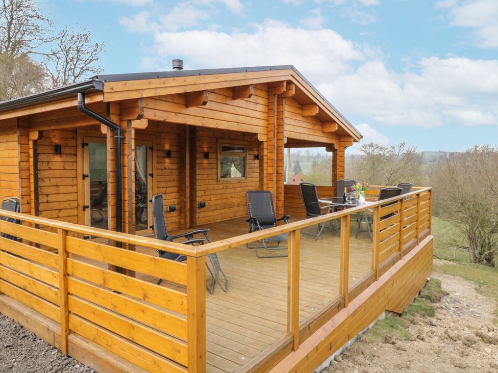 An outdoor deck with chairs and a table at Manor Farm Lodges - Red Kite Lodge Newtown