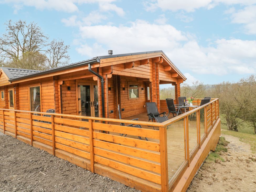 A log cabin with a deck and seating area at Manor Farm Lodges - Red Kite Lodge in Newtown