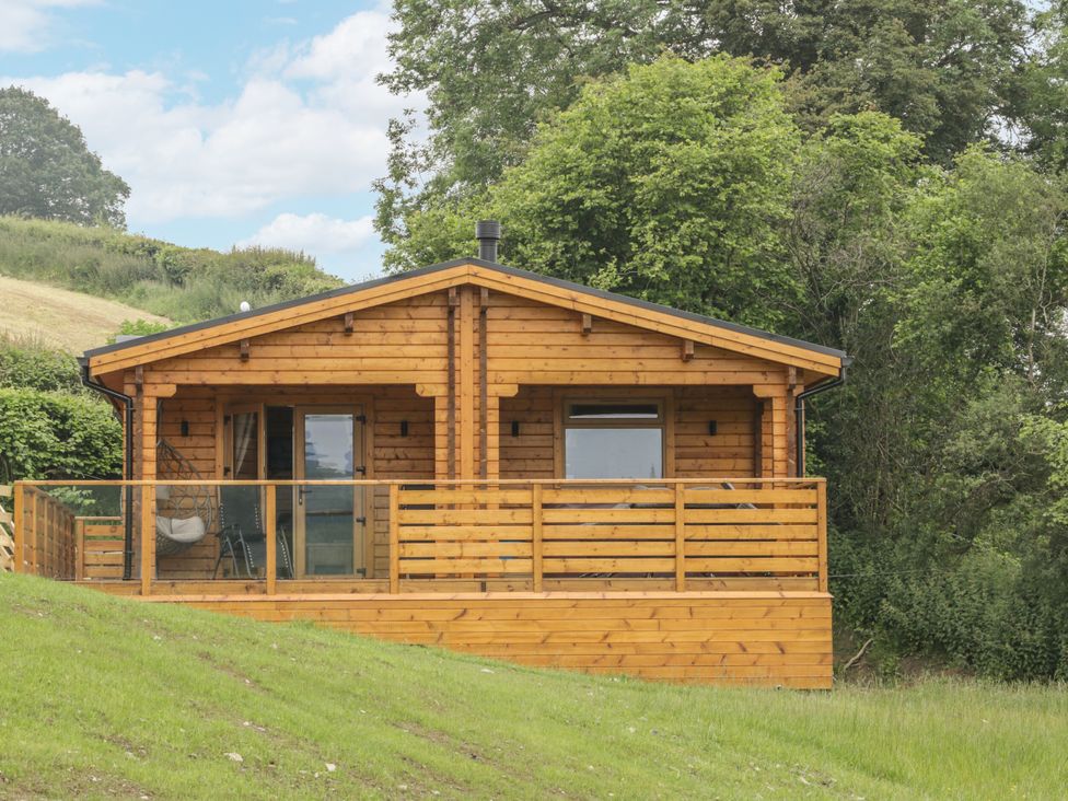 A log cabin with a deck and railing at Manor Farm Lodges - Red Kite Lodge Newtown