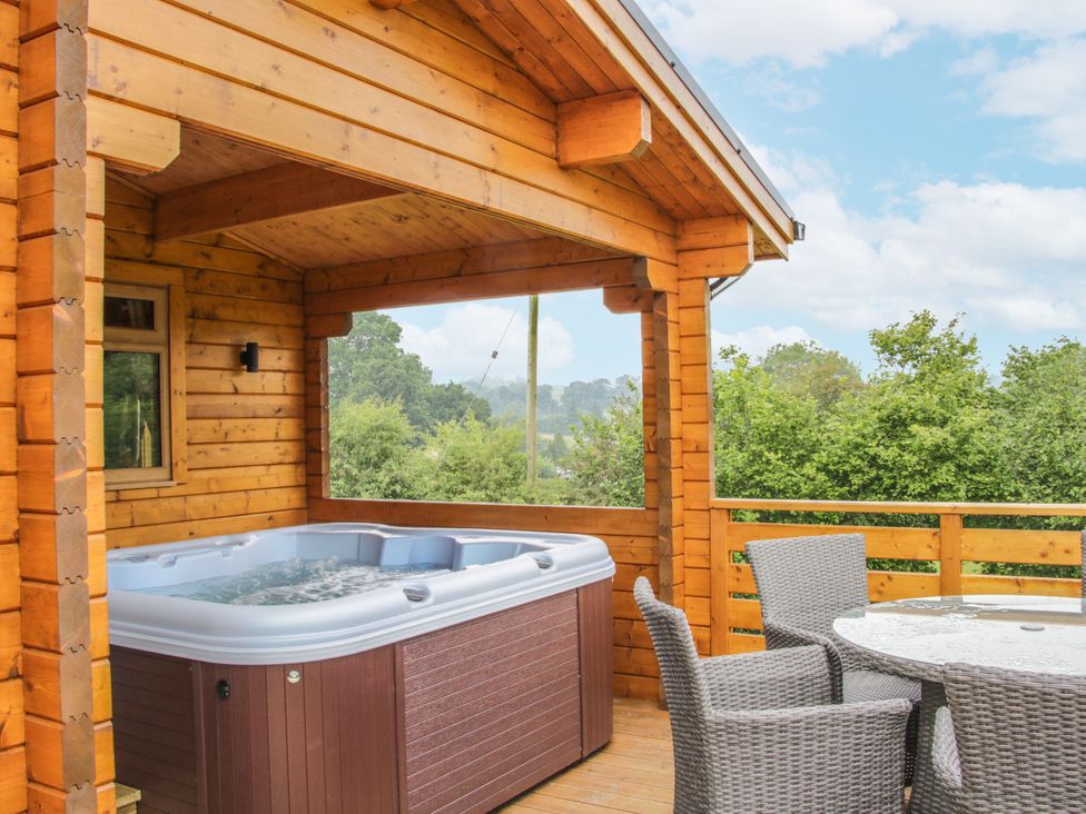 An outdoor space with a hot tub and seating area at Manor Farm Lodges - Red Kite Lodge in Newtown