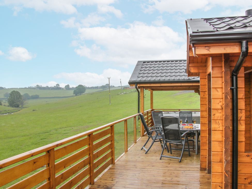 An outdoor deck with table and chairs at Manor Farm Lodges - Dragon Lodge, Newtown