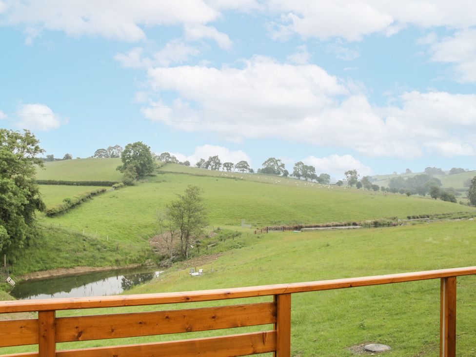 A scenic view of grass hills and a pond at Manor Farm Lodges - Dragon Lodge, Newtown