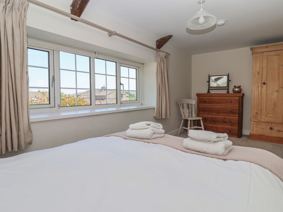 A bedroom with a bed, towels, windows, chair, and dresser at Lyndhurst, Carlton-in-Coverdale, near Leyburn