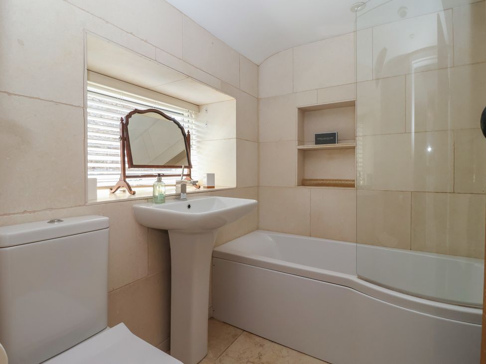 A bathroom featuring a toilet, sink, bathtub, and mirror at Lyndhurst in Carlton-in-Coverdale, near Leyburn