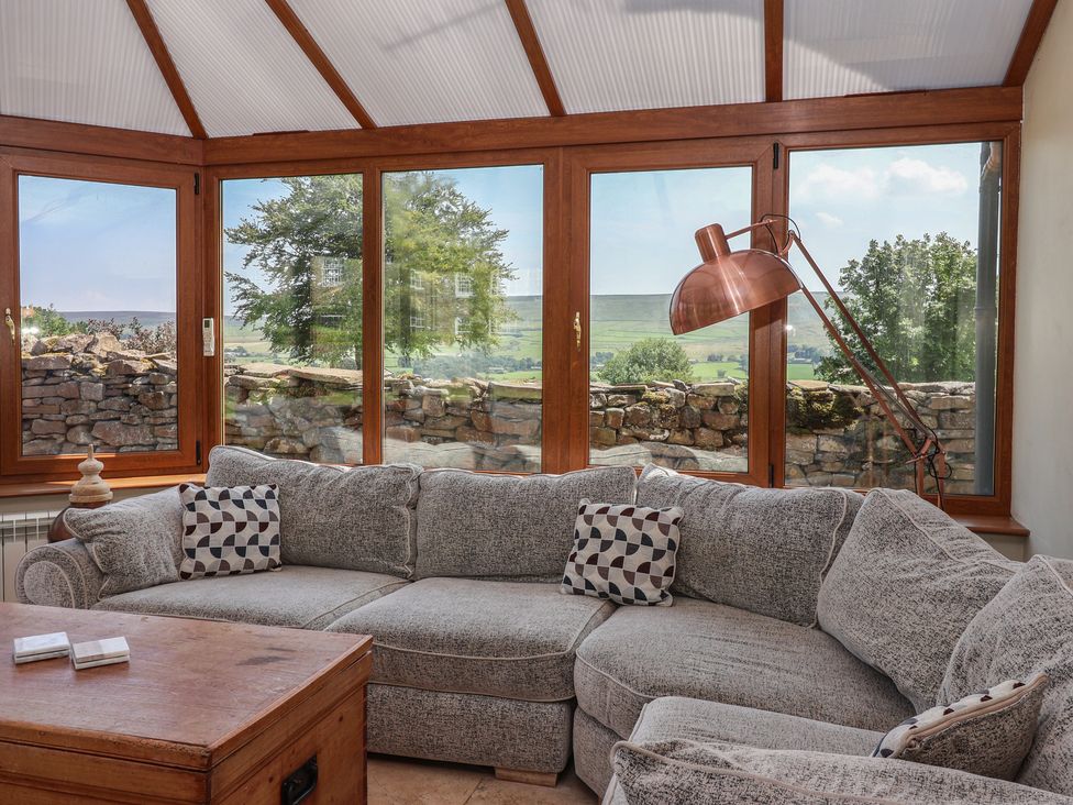 A conservatory with a sofa and table at Lyndhurst in Carlton-in-Coverdale, near Leyburn