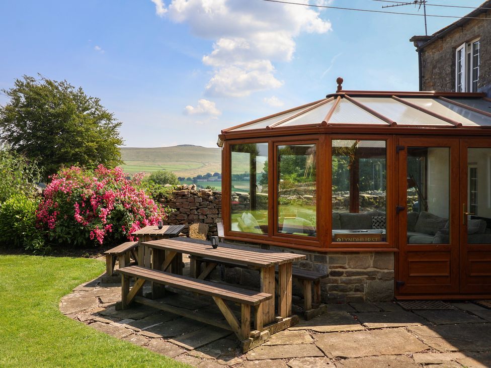 A conservatory with a wooden table and flowers at Lyndhurst Carlton-in-Coverdale near Leyburn