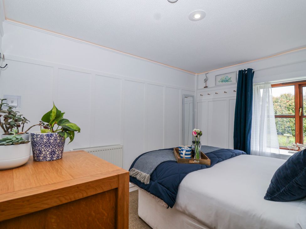 A bedroom with a bed and plants at Lily Cottage in Looe