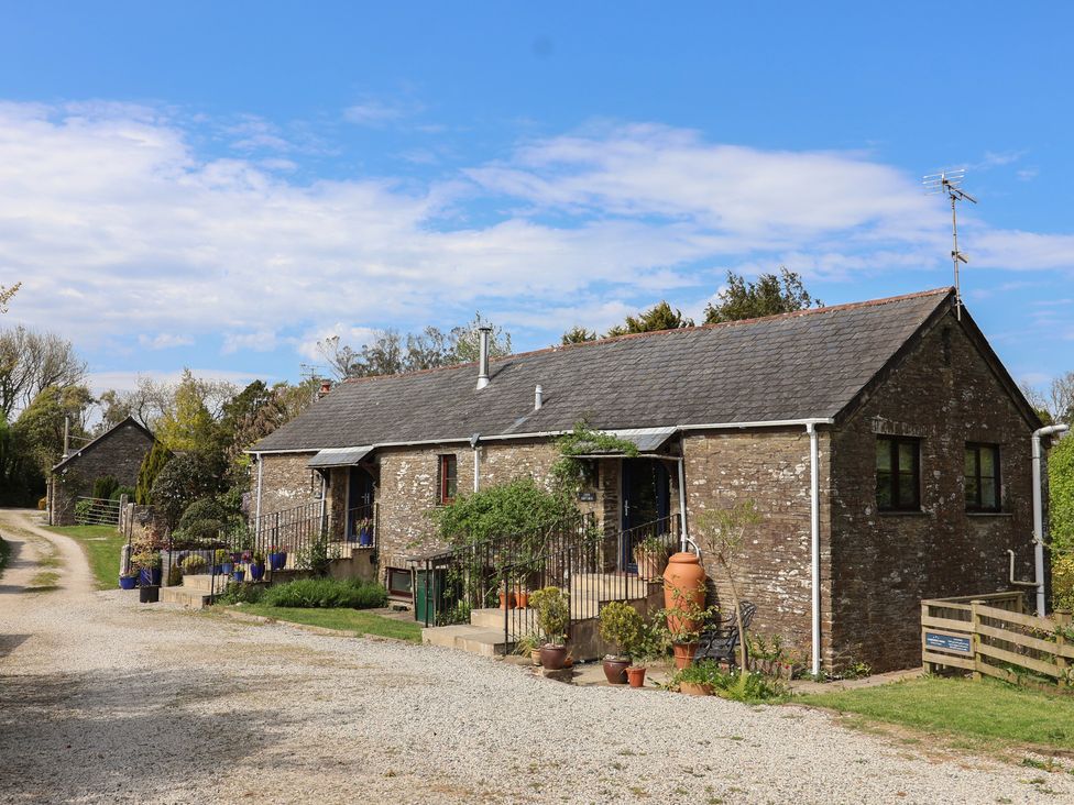A stone building with plants and gravel path at Lily Cottage in Looe