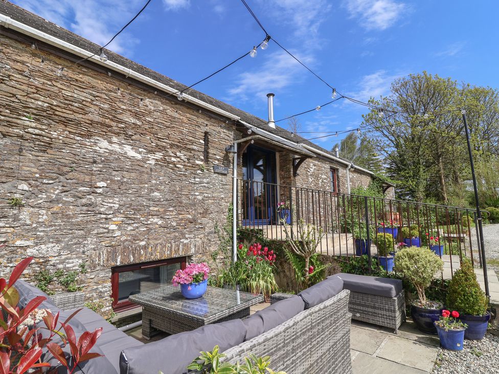 An outdoor seating area with a stone wall at Lily Cottage Looe