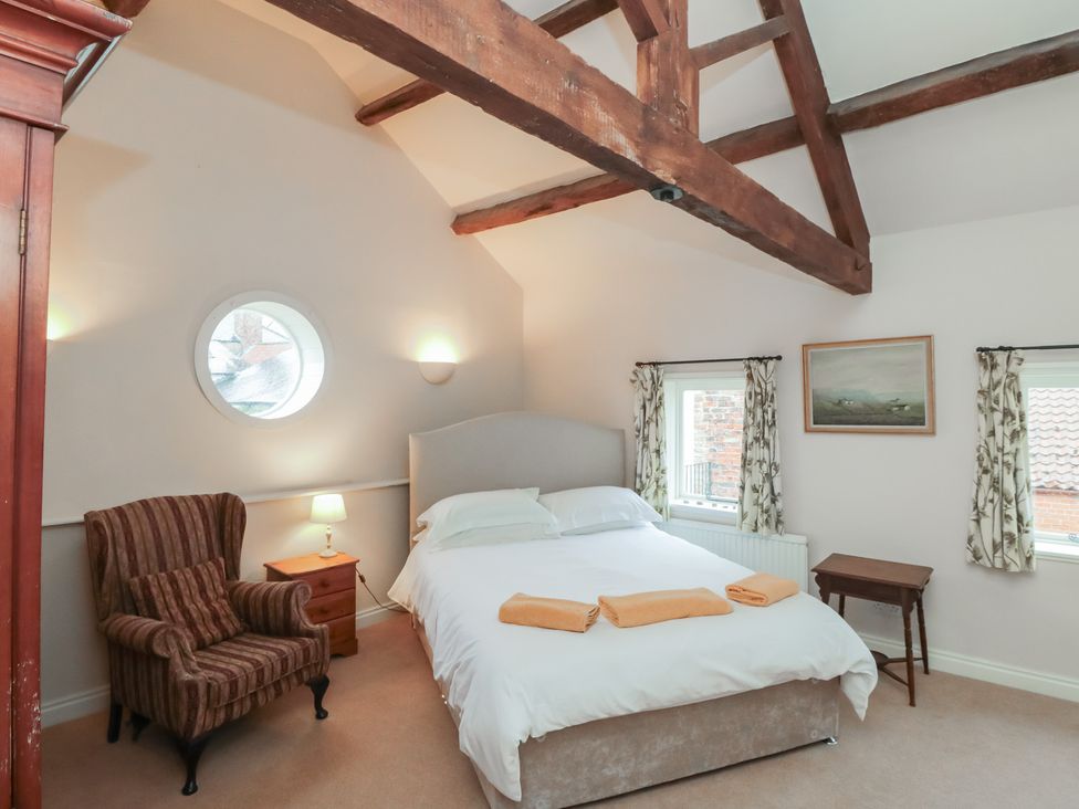 A bedroom with a bed and armchair at The Old Milk House 