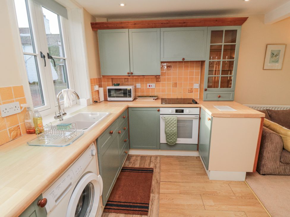 A kitchen with cabinets, sink, microwave, and washing machine at The Old Milk House near Hutton Rudby