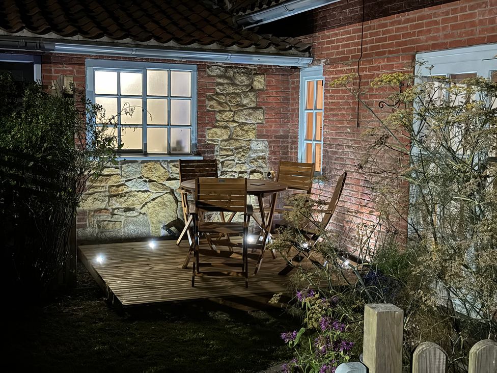 A garden with a wooden table and chairs at Gables Cottage in Market Rasen