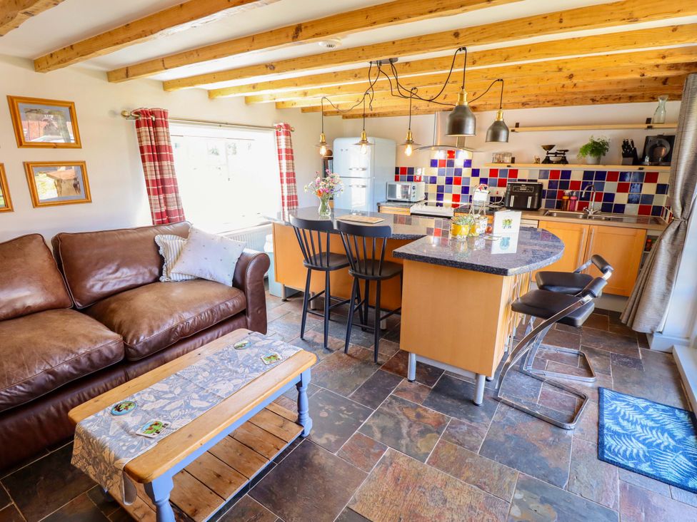 A kitchen with bar stools and a coffee table at Gables Cottage in Market Rasen