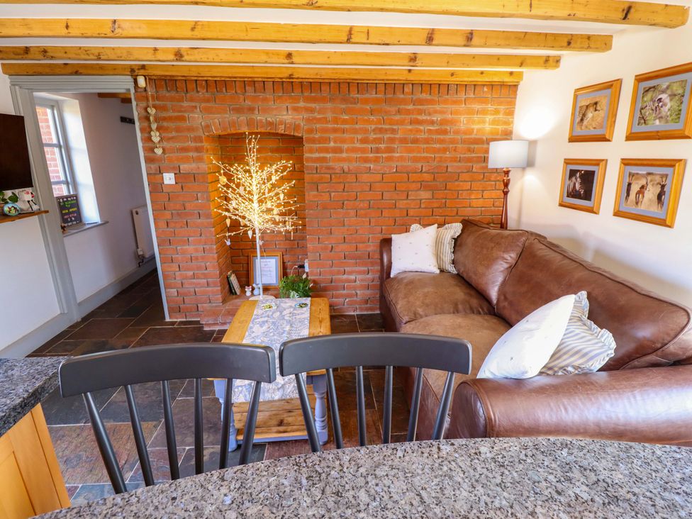 A living room with a sofa, table, and lamp at Gables Cottage in Market Rasen