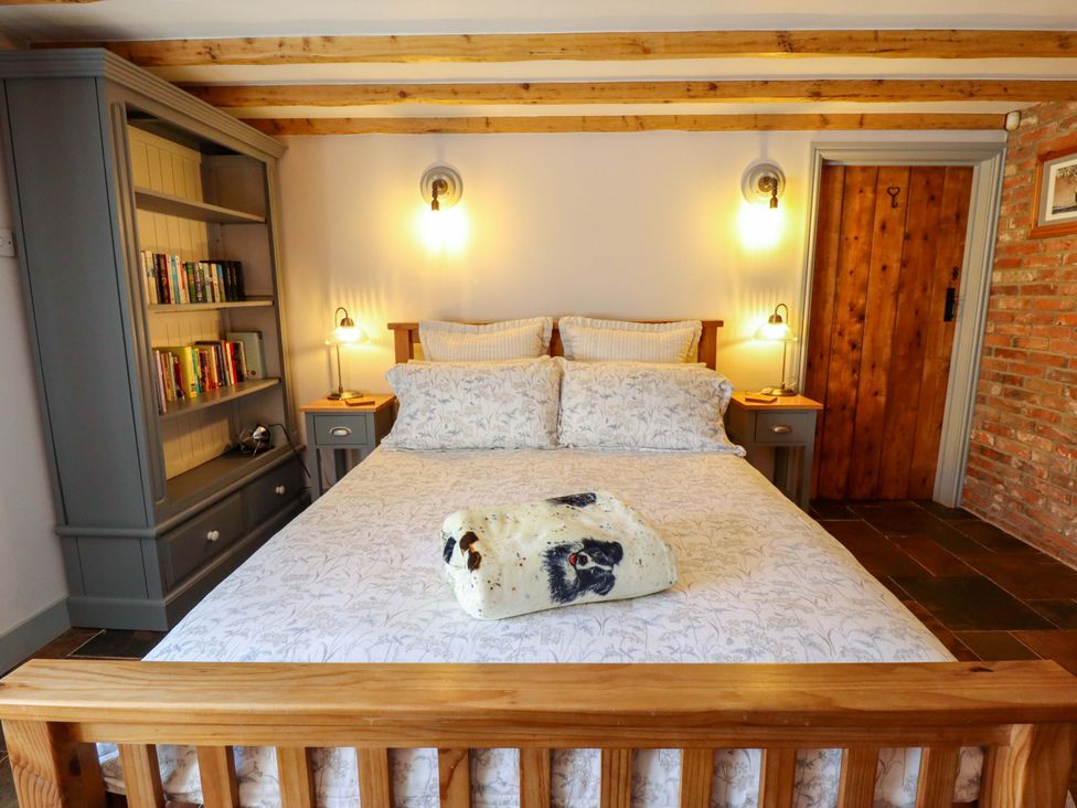 A bedroom with a bed and bookshelf at Gables Cottage in Market Rasen