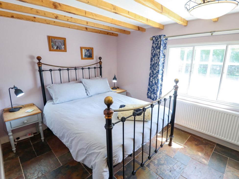A bedroom with a bed and windows at Gables Cottage in Market Rasen