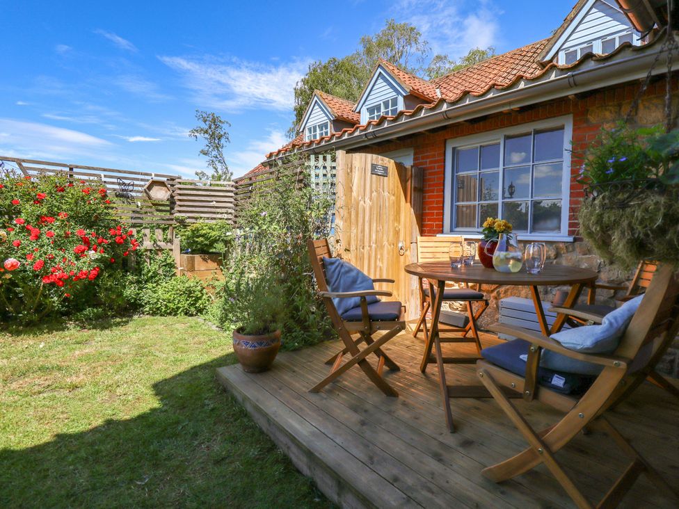 A deck area with a table and chairs in the garden at Gables Cottage Market Rasen