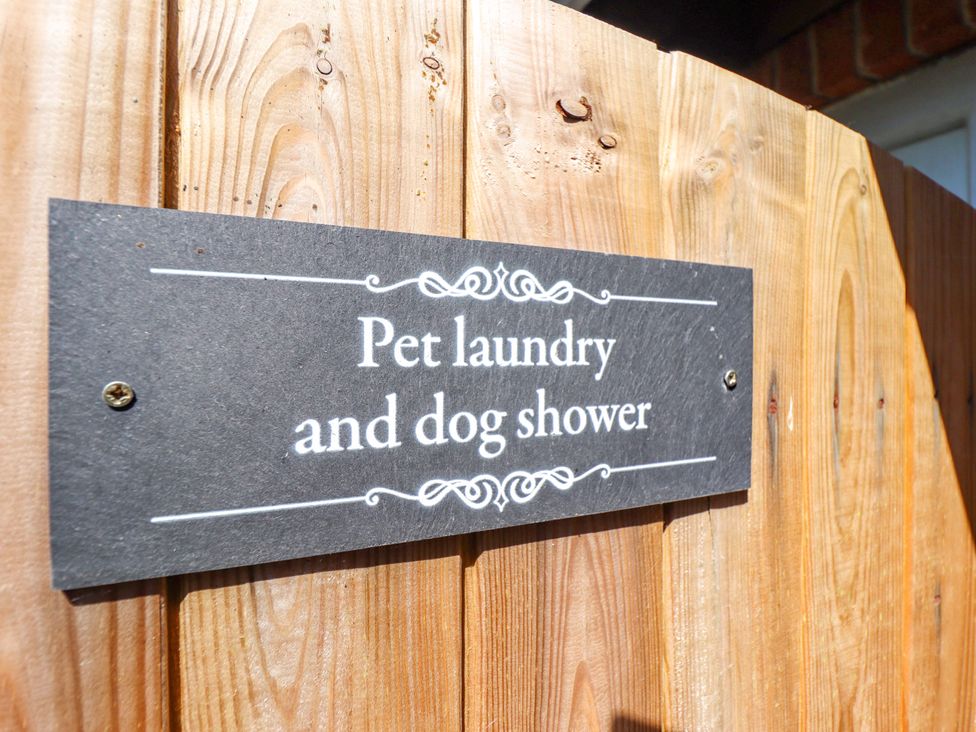 A sign stating 'Pet laundry and dog shower' on a wooden fence at Gables Cottage in Market Rasen