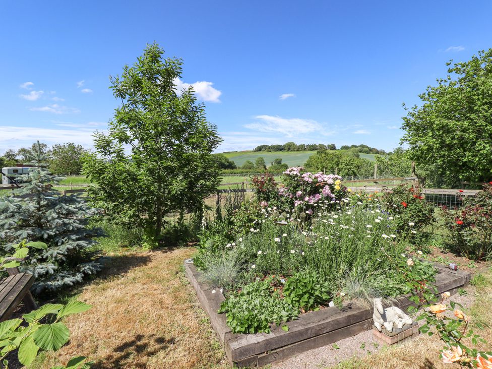 A garden with flower beds and trees at Gables Cottage Market Rasen