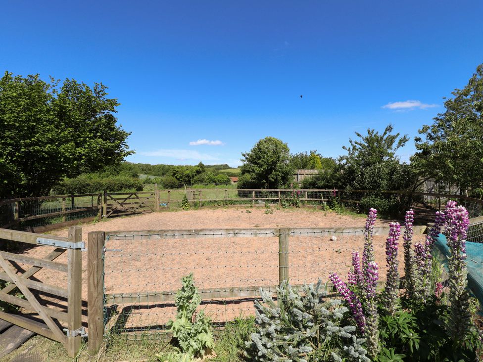 An outdoor area with a fenced riding ring and flowers at Gables Cottage in Market Rasen