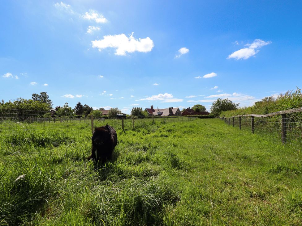 An outdoor view of a field with grass and a house in the background at Gables Cottage Market Rasen