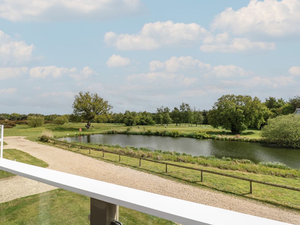 A view of a lake and trees from a balcony at Links View in Fritton