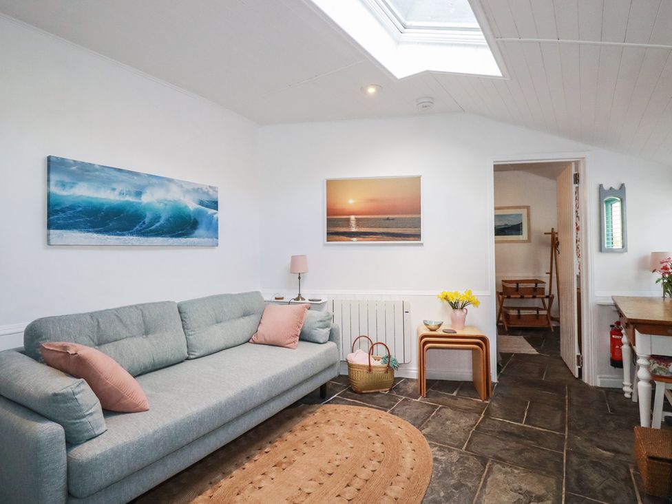 A living room with a sofa and paintings at Smugglers Cottage Trebarwith Strand near Tintagel