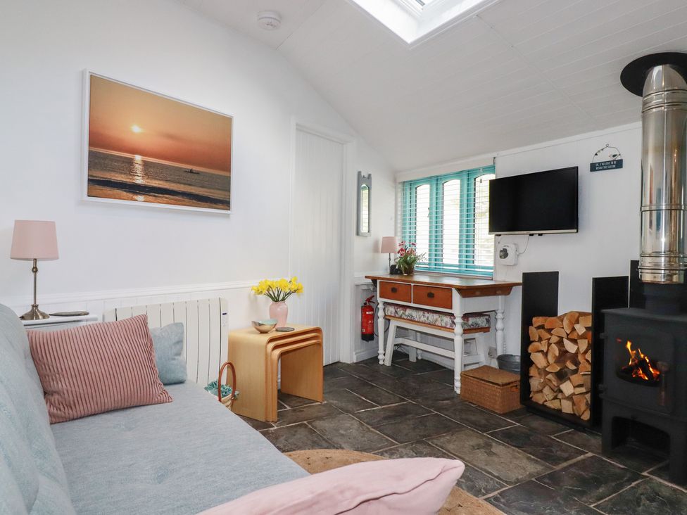 A living room with a sofa, television, and fireplace at Smugglers Cottage in Trebarwith Strand near Tintagel