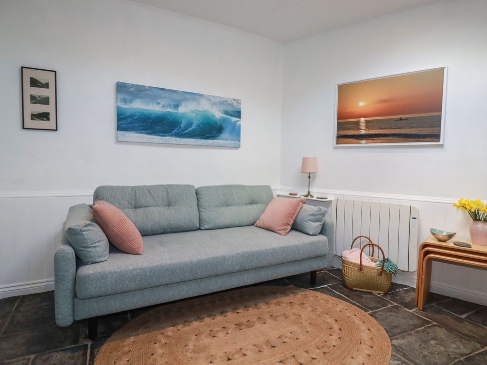 A living room with a sofa and wall art at Smugglers Cottage in Trebarwith Strand near Tintagel