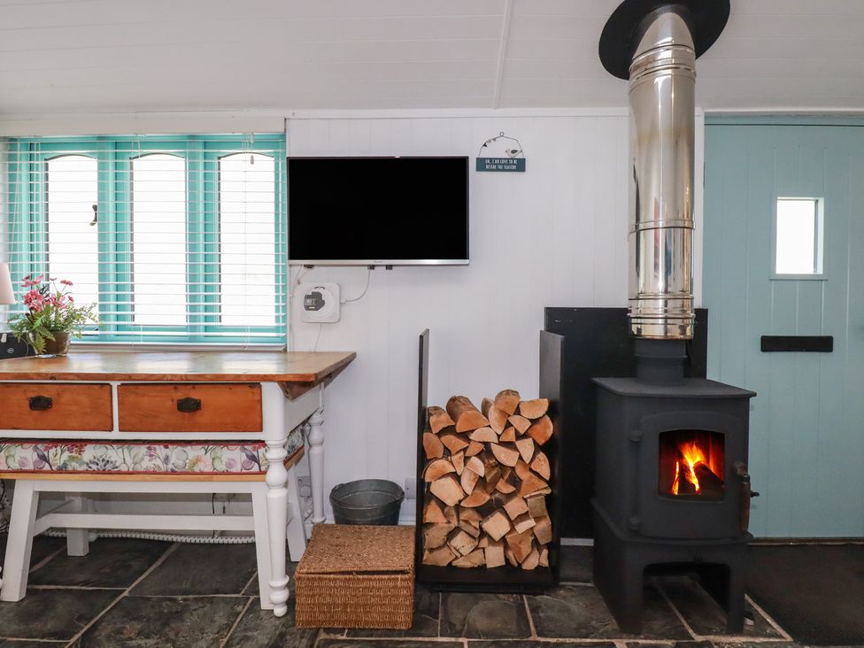 A living room with a fireplace and a television at Smugglers Cottage in Trebarwith Strand near Tintagel