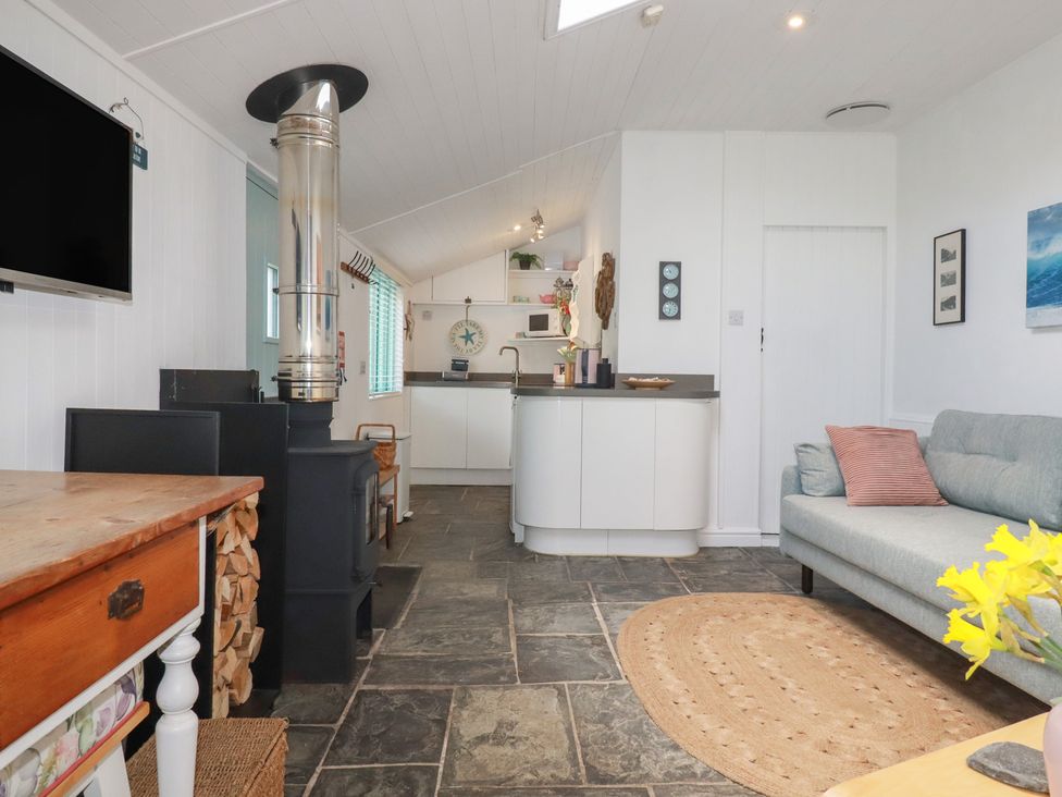 A living room with a stove and sofa at Smugglers Cottage in Trebarwith Strand near Tintagel