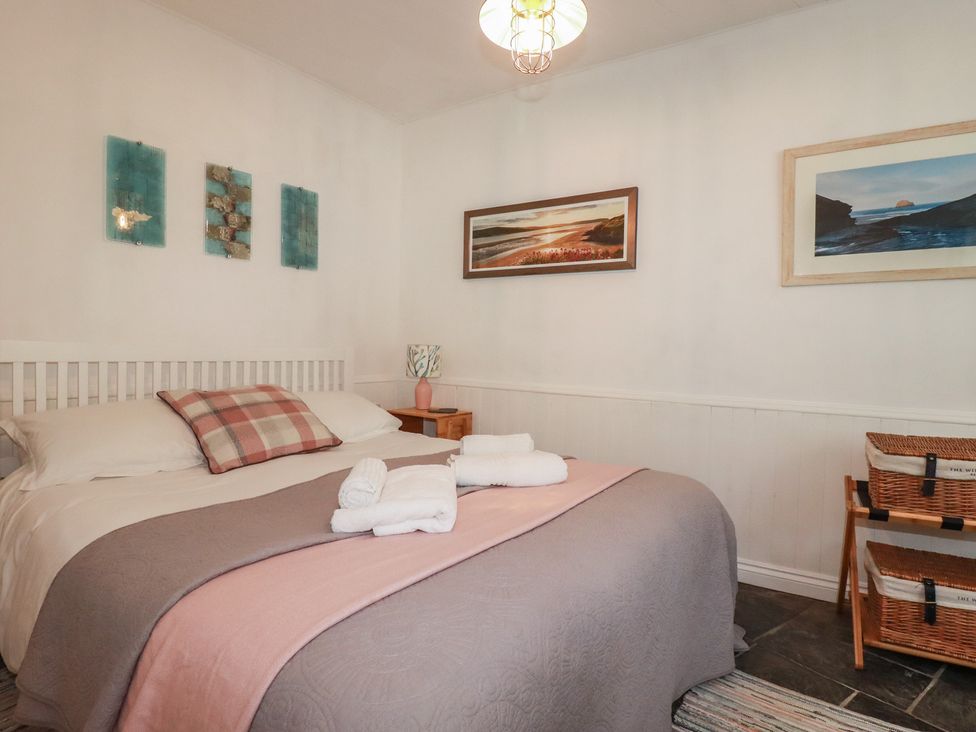 A bedroom with a bed and nightstand at Smugglers Cottage in Trebarwith Strand near Tintagel