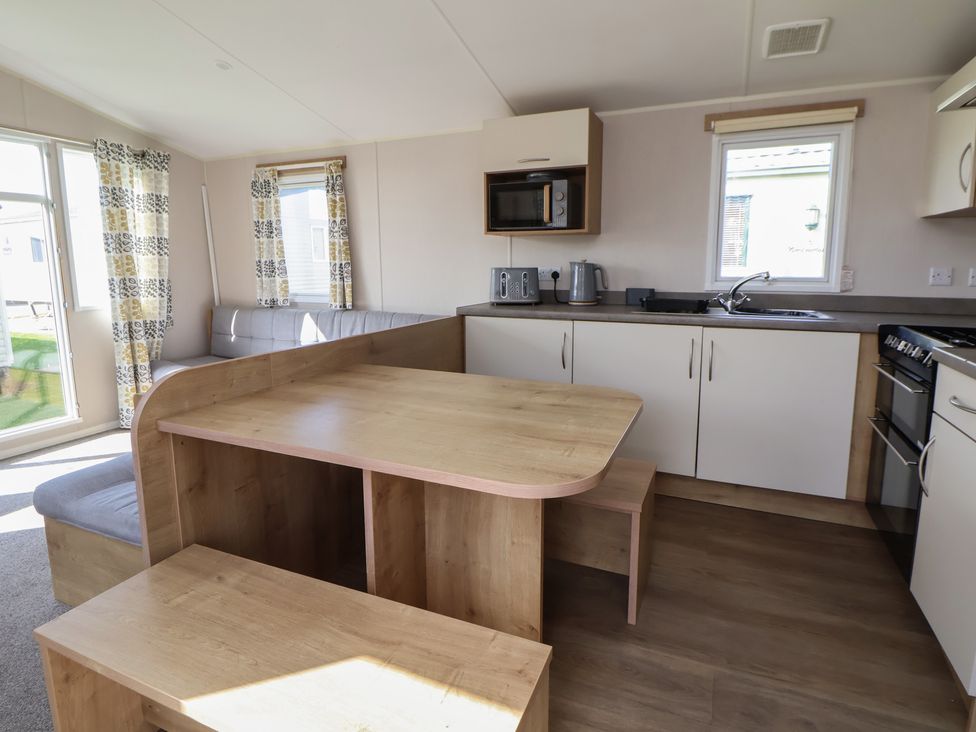 A kitchen with table, bench, microwave, and stove at K2 Static Caravan