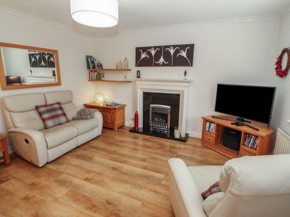 A living room with a fireplace and television at Riverside Cottage in Cockermouth