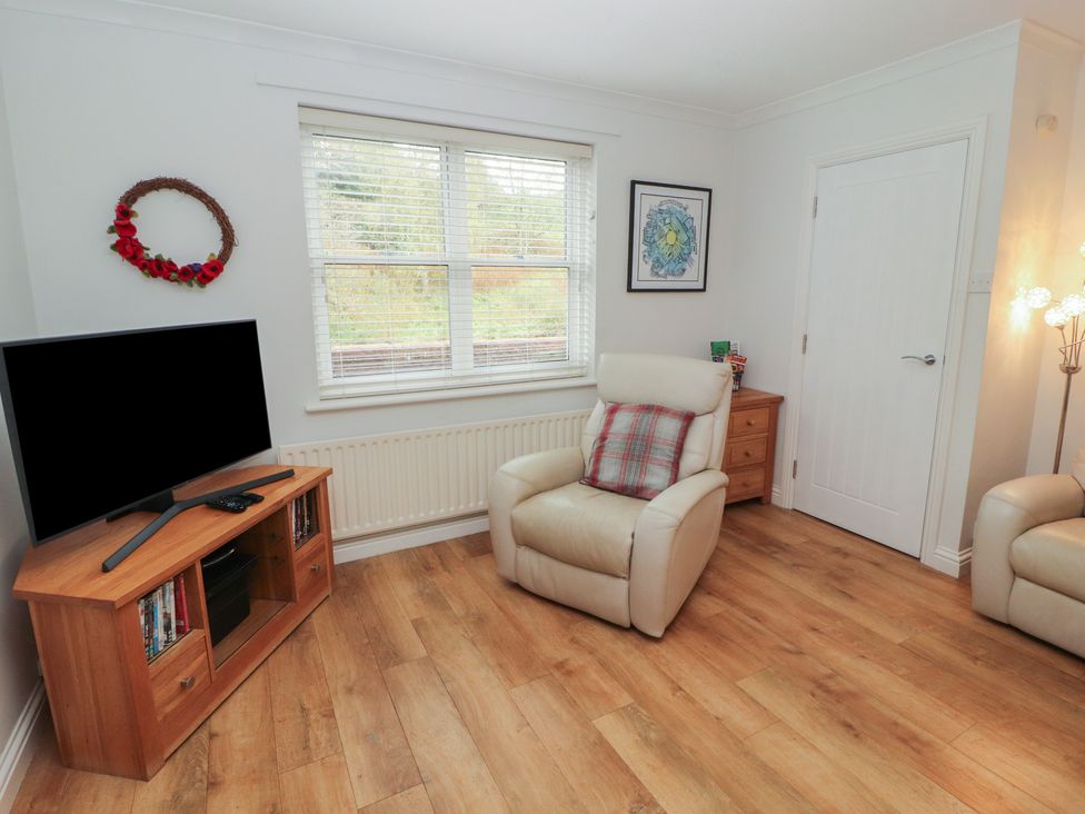 A living room with a television and armchair at Riverside Cottage in Cockermouth