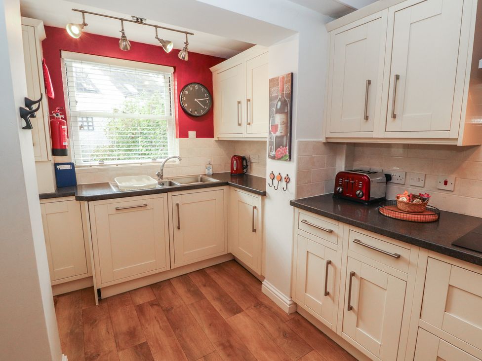 A kitchen with cabinets, sink, and appliances at Riverside Cottage in Cockermouth