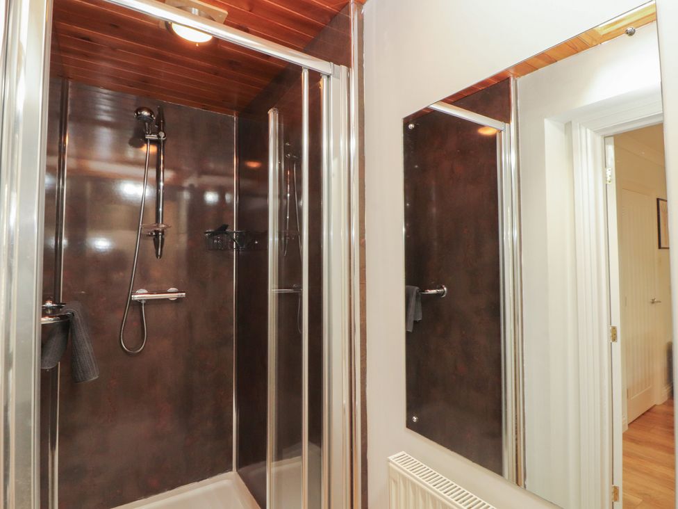 A bathroom with a shower and mirror at Riverside Cottage in Cockermouth