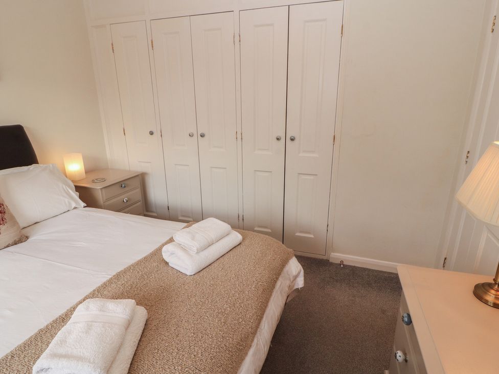 A bedroom with a bed and wardrobe at Riverside Cottage in Cockermouth