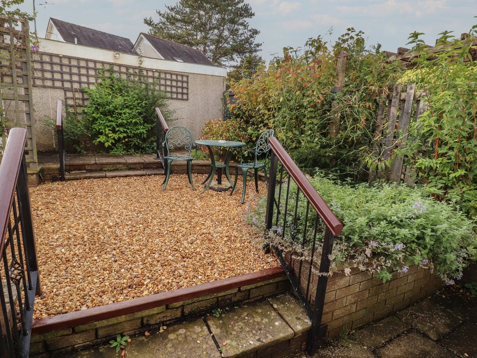 A garden with gravel, chairs, and a table at Riverside Cottage in Cockermouth