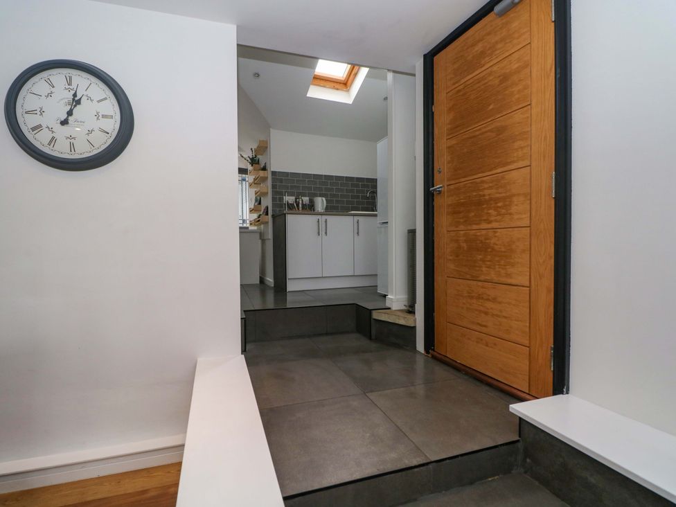 A hallway with a clock and a front door at Broad Beams Parkgate near Neston