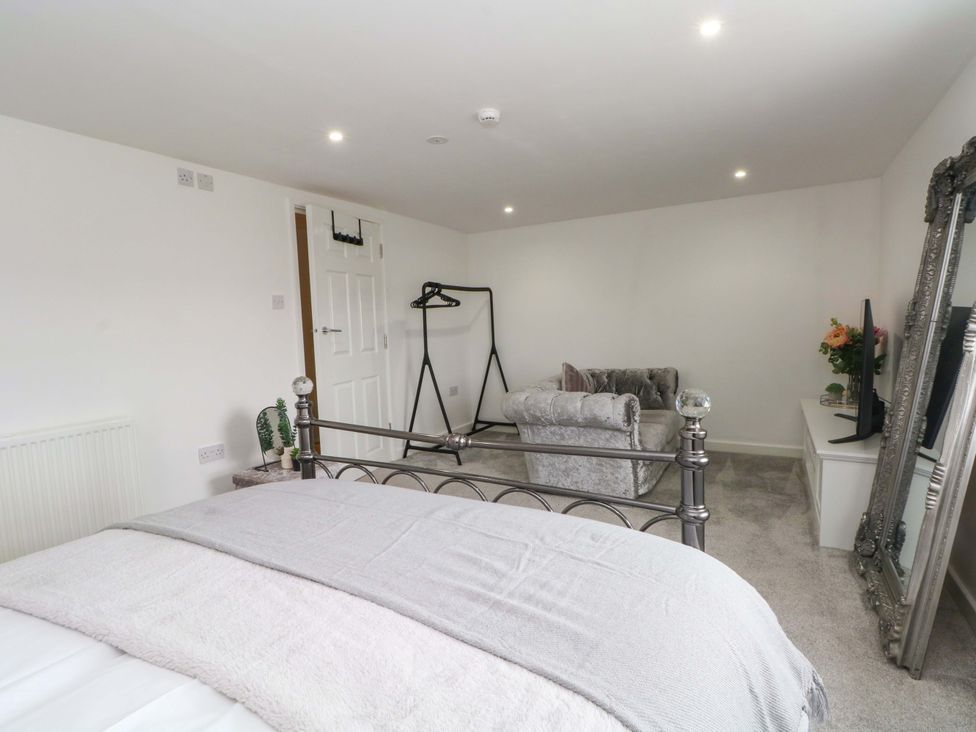 A bedroom with a bed and a sofa at Broad Beams Parkgate near Neston