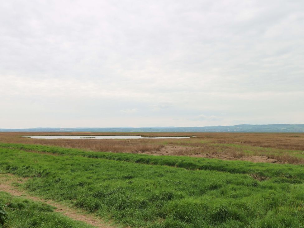 An open field with a water body in the distance at Broad Beams Parkgate near Neston