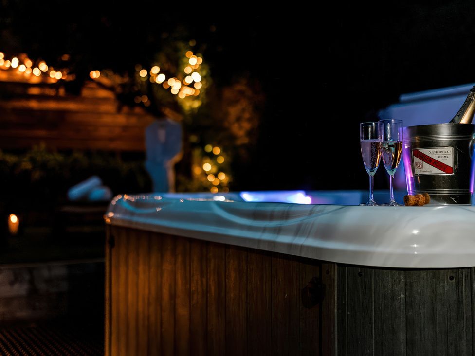 A hot tub with champagne glasses and ice bucket in an outdoor area at Carrholme Cottage, Settle
