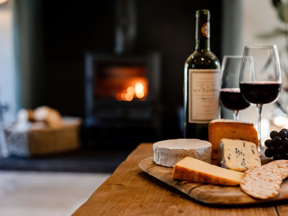 A cheese board with wine and glasses in a living room at Carrholme Cottage Settle