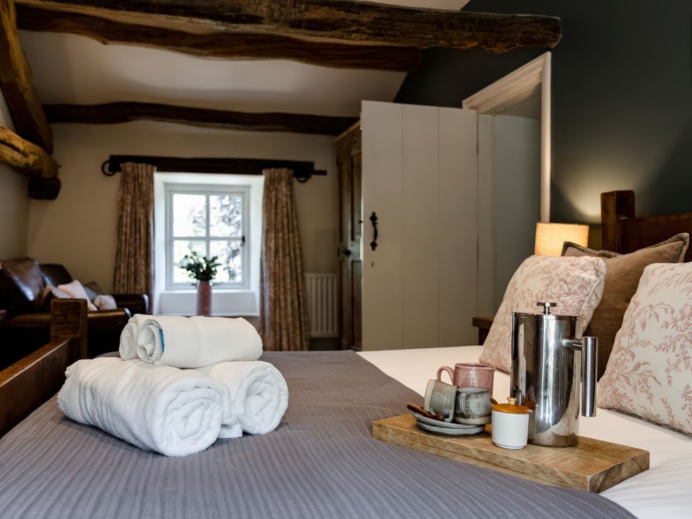 A bedroom with towels and a tea set on the bed at Carrholme Cottage Settle