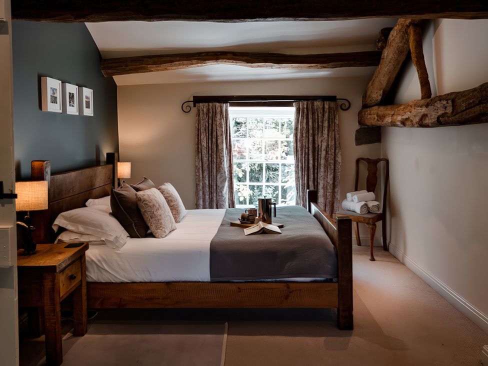 A bedroom with a bed, nightstand and window at Carrholme Cottage Settle