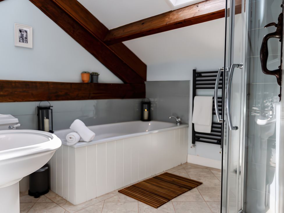 A bathroom with a bath tub, sink, and shower at Carrholme Cottage Settle