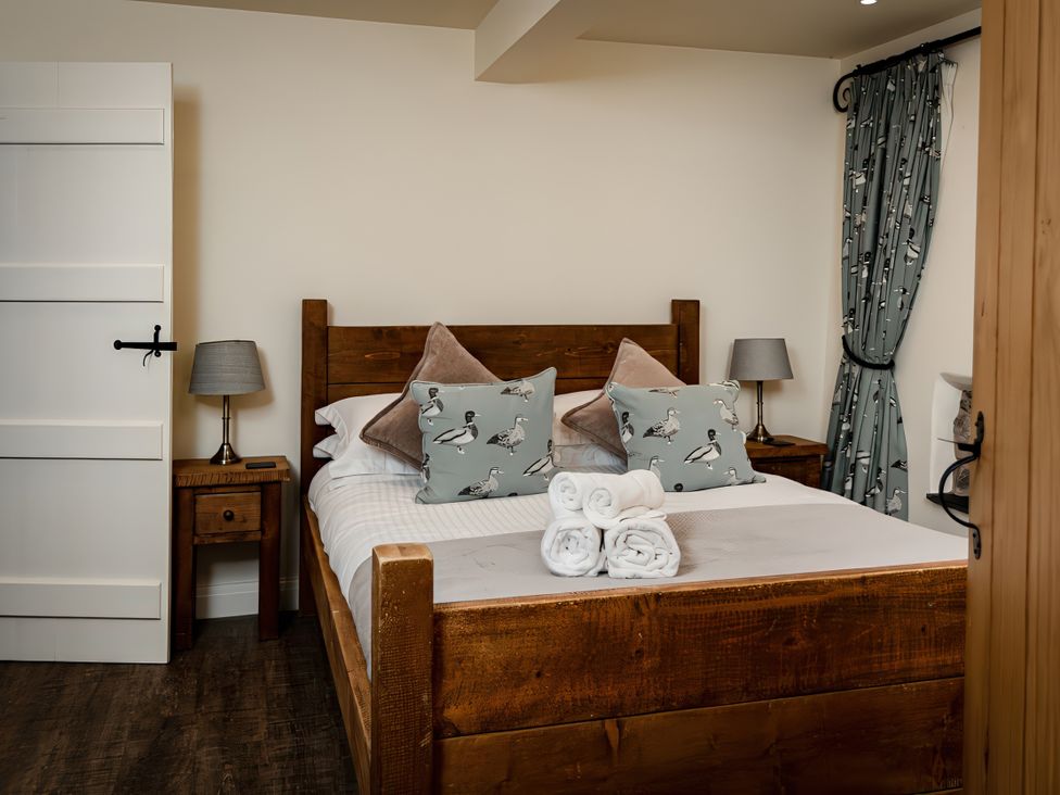 A bedroom with a wooden bed and side table at Carrholme Cottage Settle