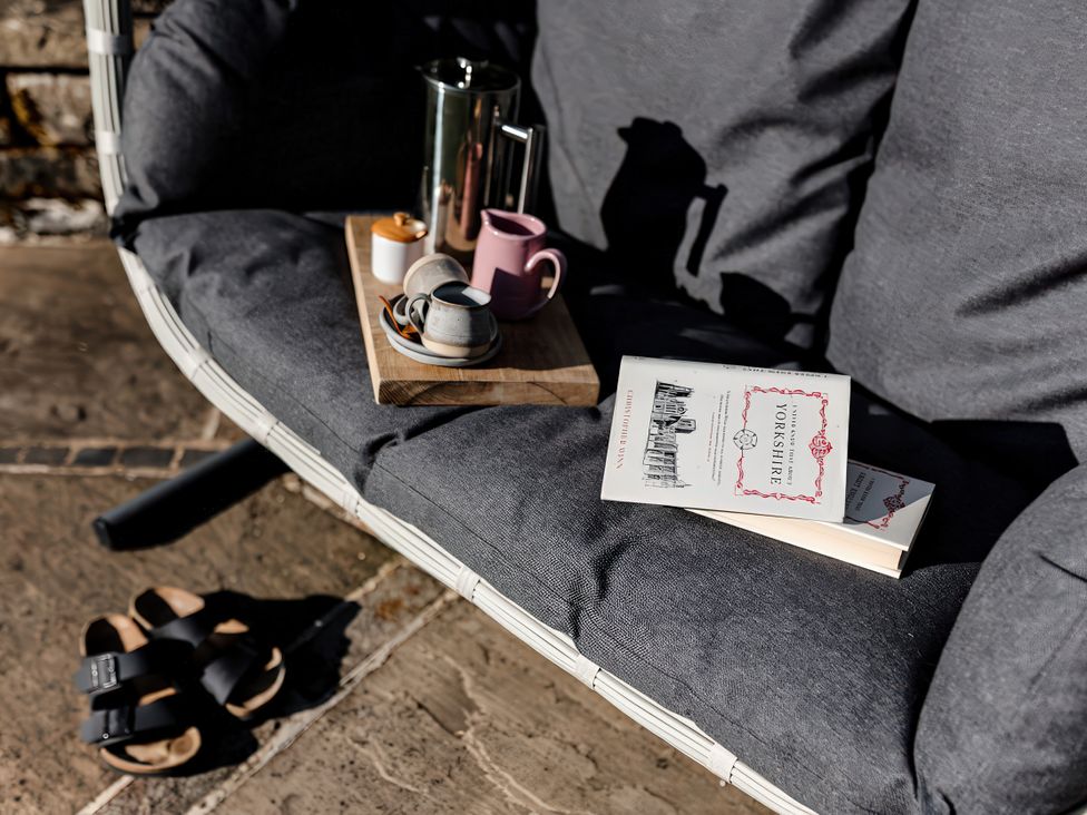 A chair with a book and coffee items at Carrholme Cottage Settle